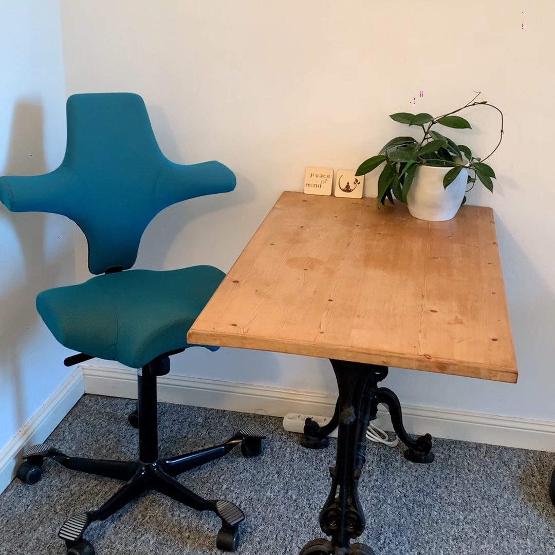 Ein ergonomischer Stuhl steht neben einem kleinen Tisch